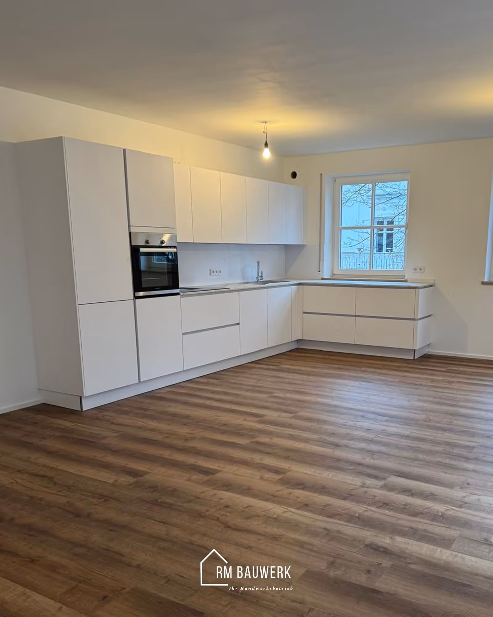 Helle Einbauküche mit Holzboden nach der Renovierung durch RM-Bauwerk