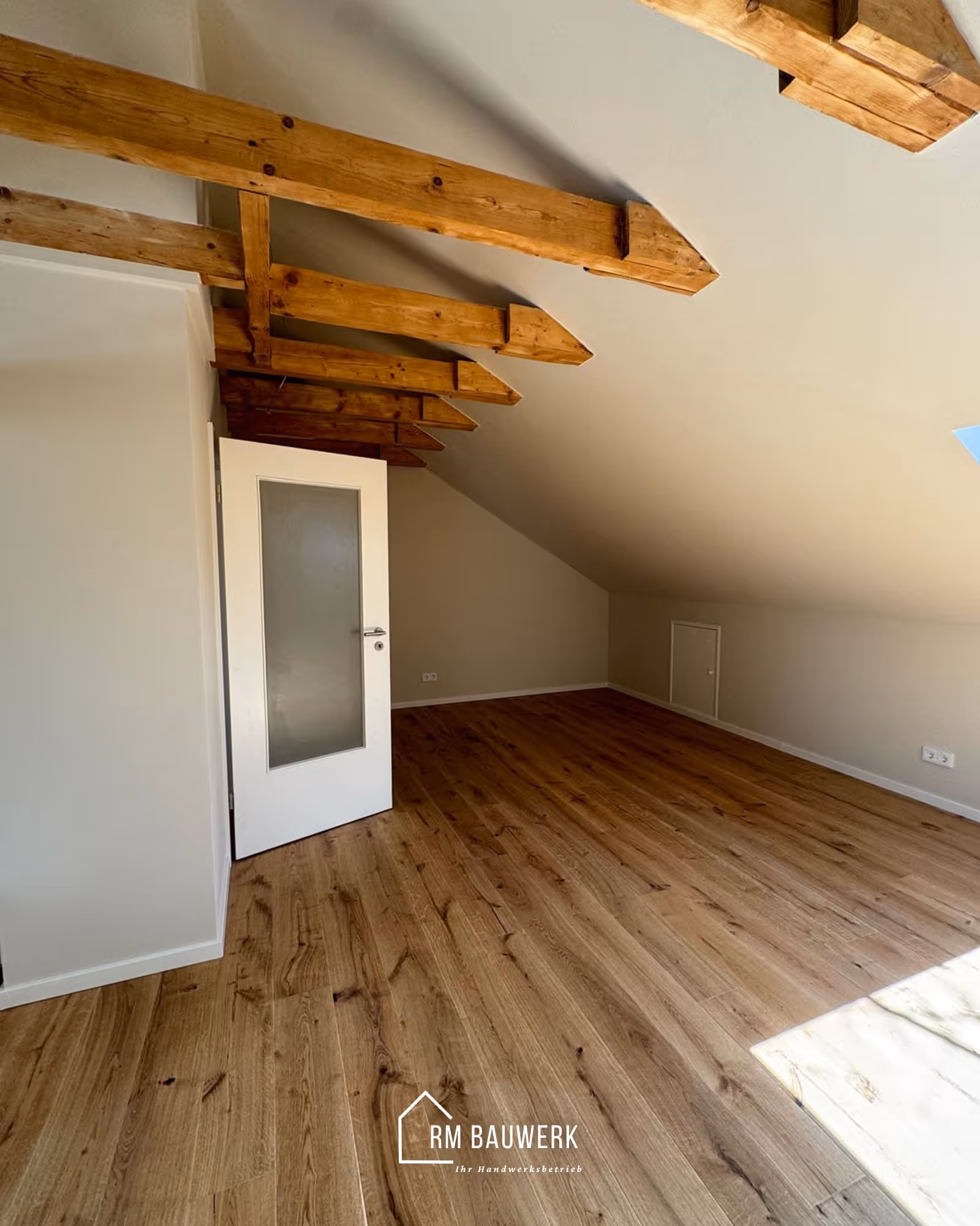 Wohnraum mit freigelegten Holzbalken und Holzboden nach dem Dachgeschossausbau