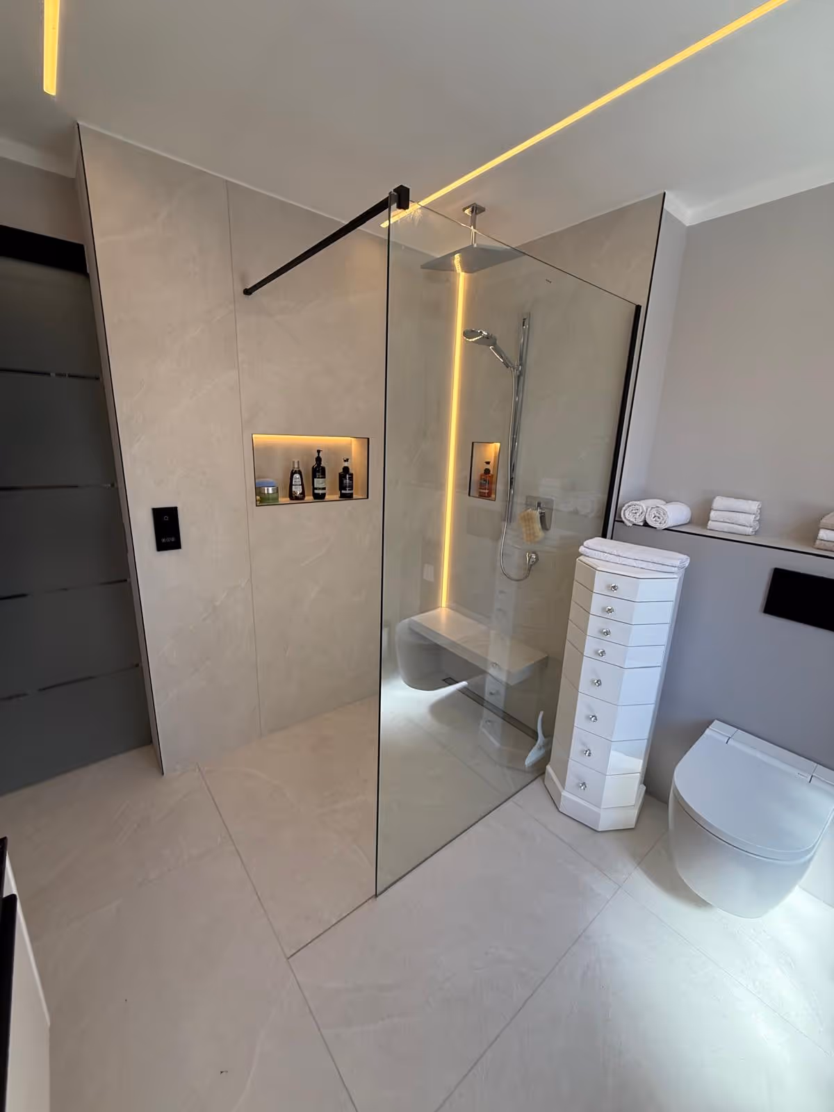 Saniertes Bad in München mit Glasduschwand, LED-Lichtband an der Decke und Hänge-WC