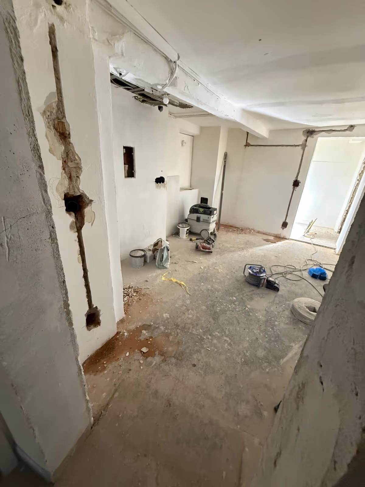 Entkernte Wohnung in Augsburg mit aufgestemmten Wandschlitzen und Werkzeug auf dem freigelegten Boden