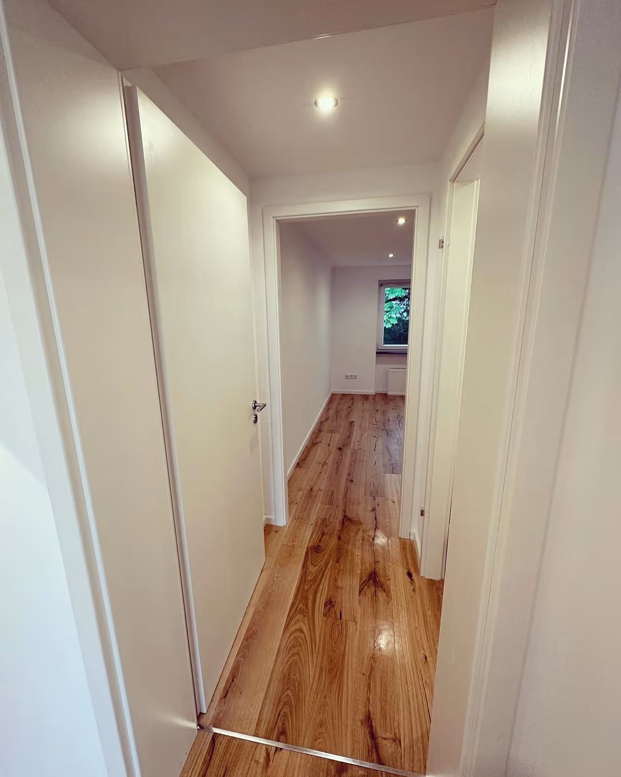 Flur mit Holzdielen und weißen Innentüren in einer kernsanierten Wohnung in München