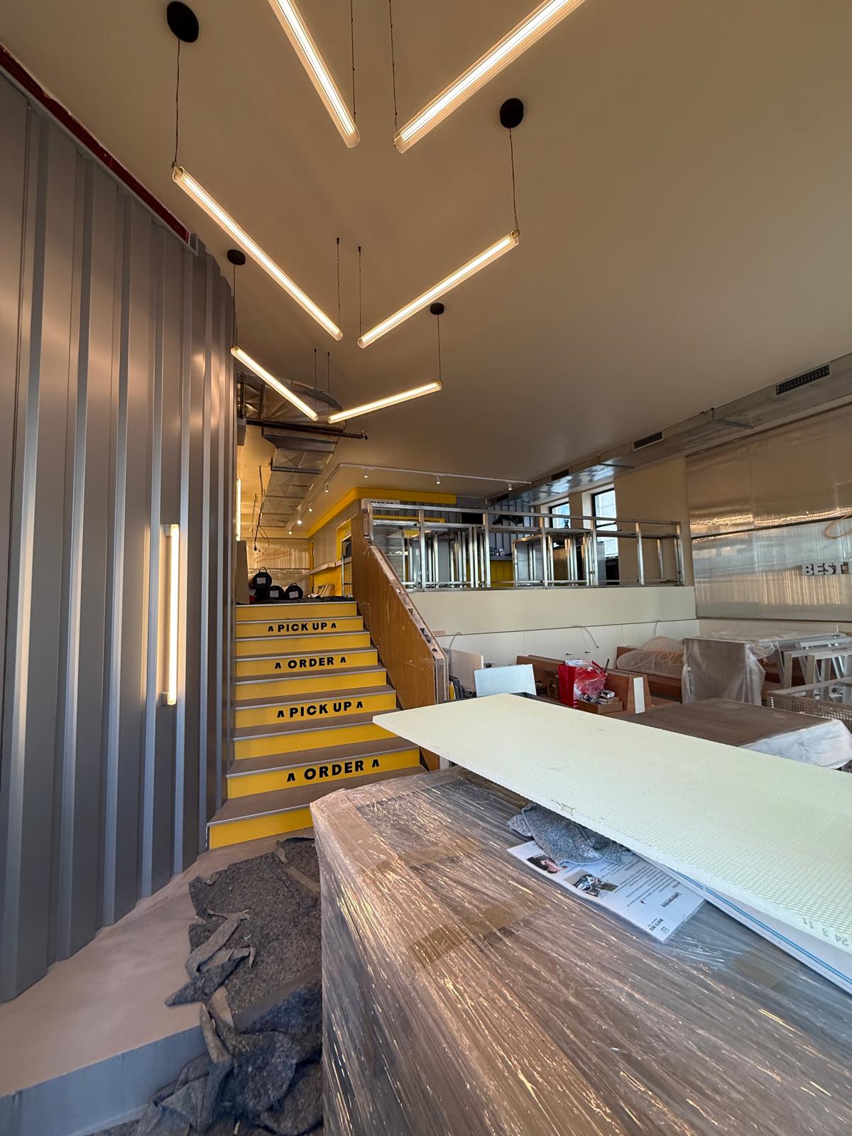 Gastraum mit Treppe, Lichtbändern und Holztresen im umgebauten Goldies Smashburger in München