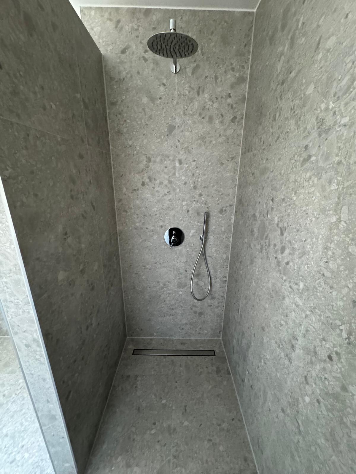 Bodengleiche Dusche mit Wandfliesen in Terrazzo-Optik in einer sanierten Eigentumswohnung in Augsburg