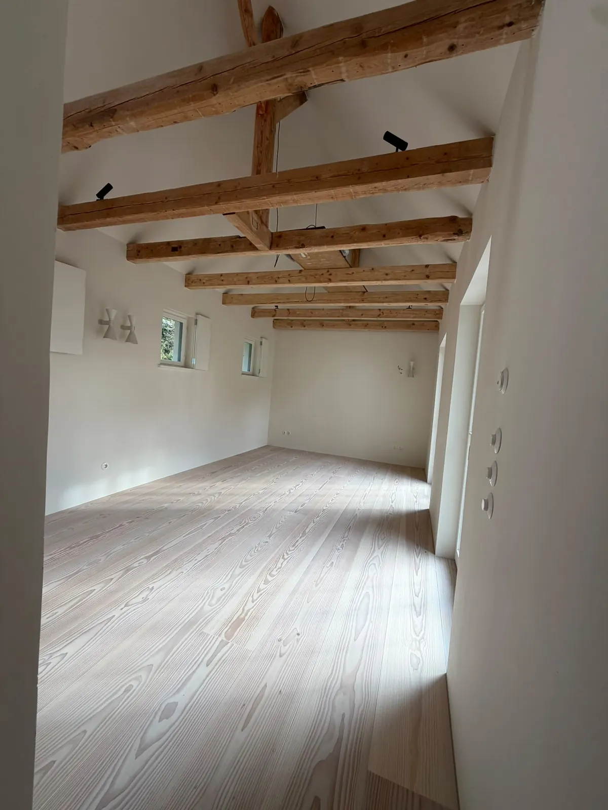 Dachgeschoss mit sichtbaren Holzbalken nach der Sanierung am Pilsensee