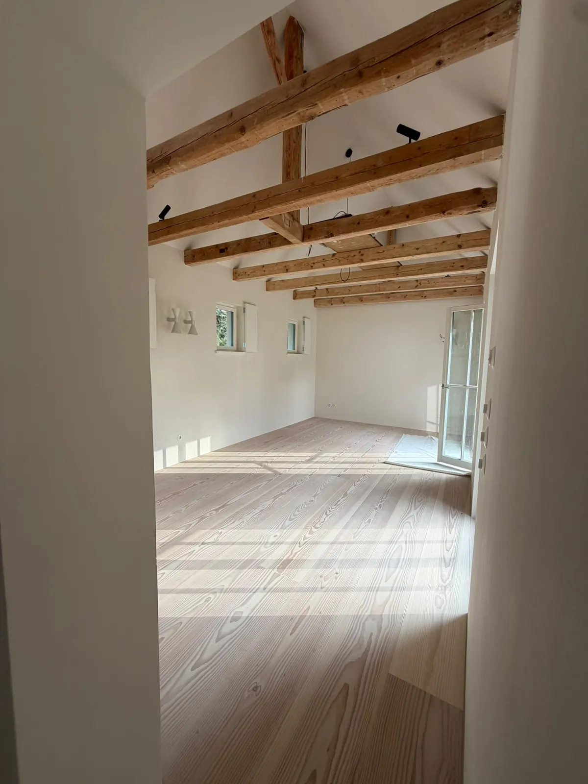 Langer Dachraum mit Holzbalken und hellen Holzdielen im Haus am Pilsensee