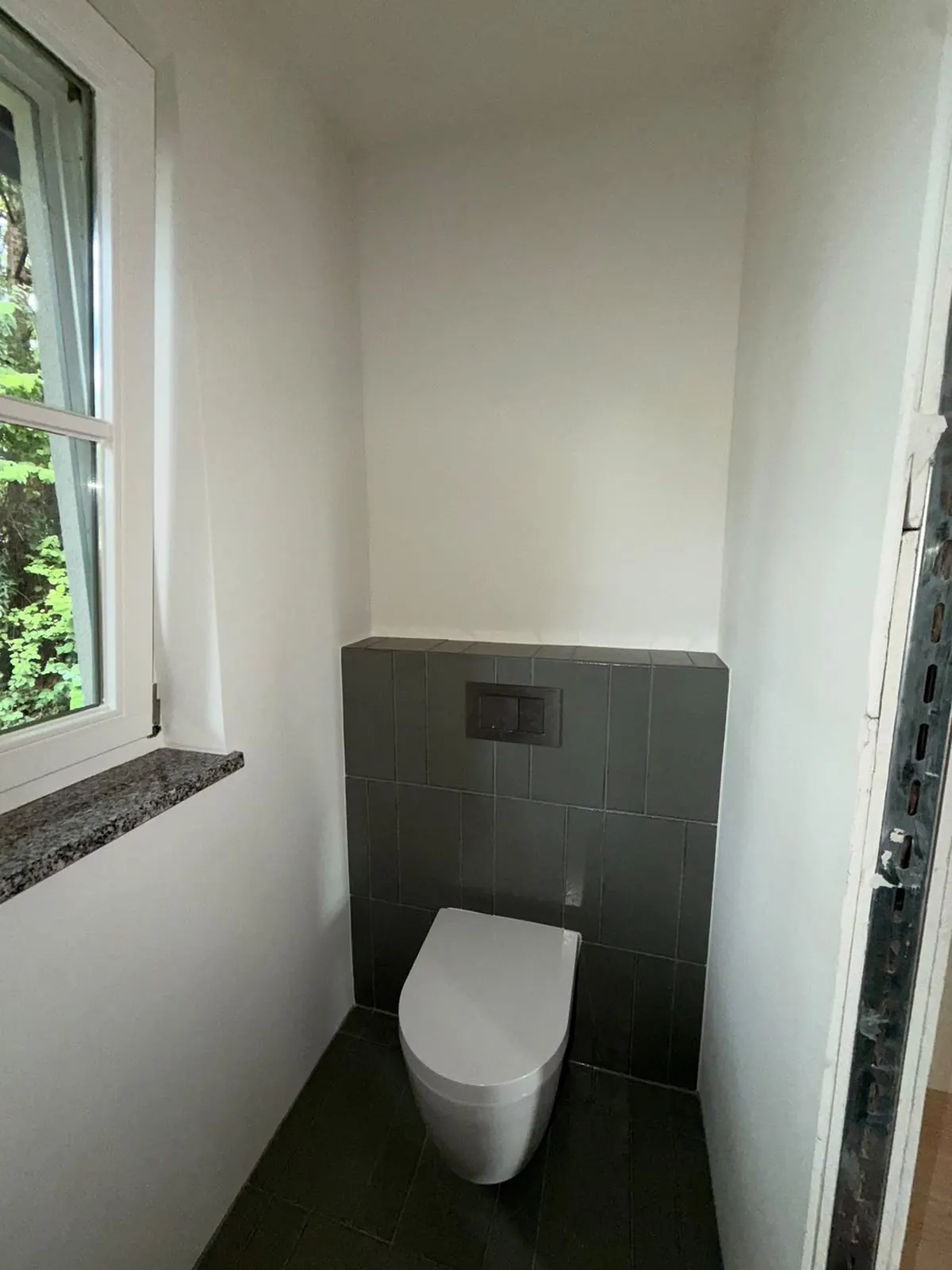 Fertiges Gäste-WC am Pilsensee mit Wand-WC und dunklen Fliesen